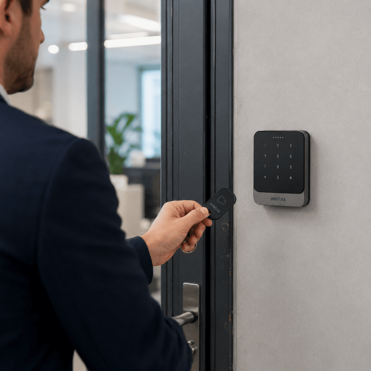 Person presenting an RFID tag to an Armatura EP20C access control reader beside an office door.